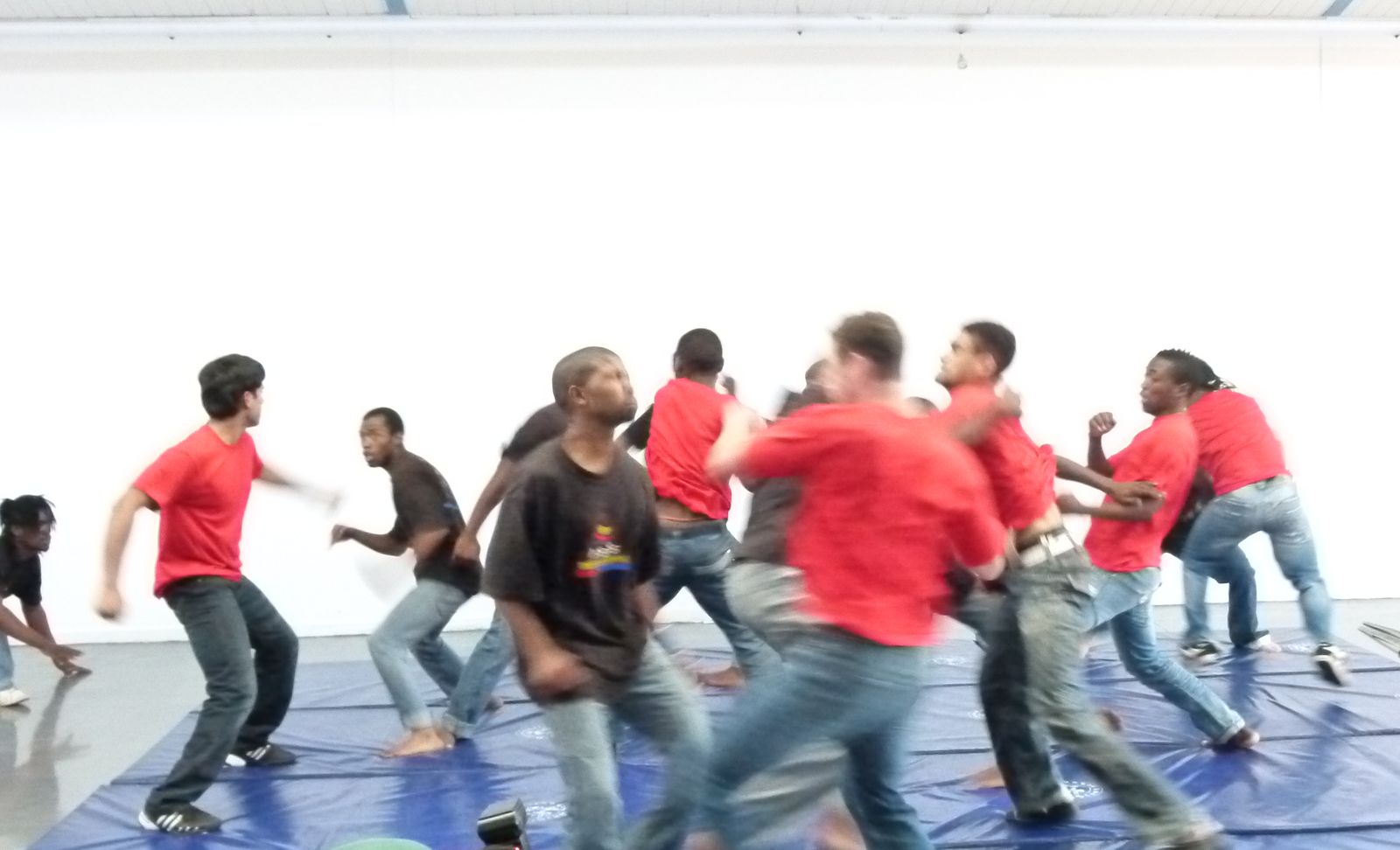 A crowded fight scene performed by trainees on blue mats
