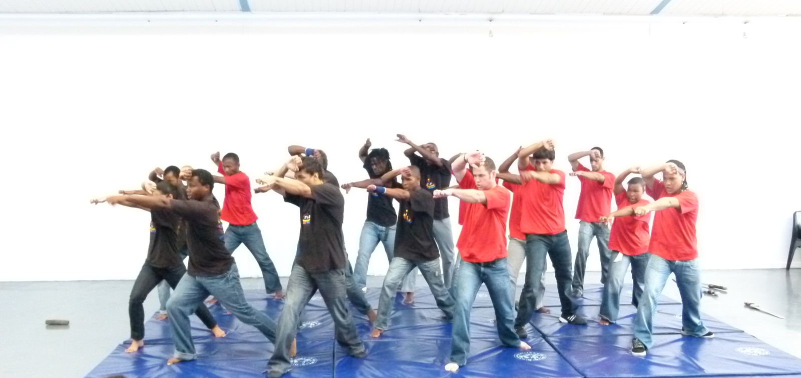 Trainees in red and black T-shirts in a synchronised fight pose