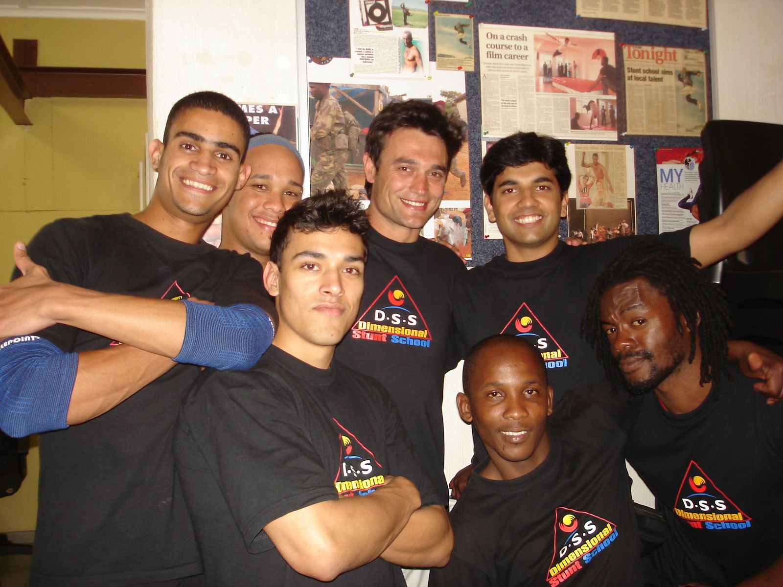 Members of the 2010 class in DSS T-shirts in front of a wall of press clippings