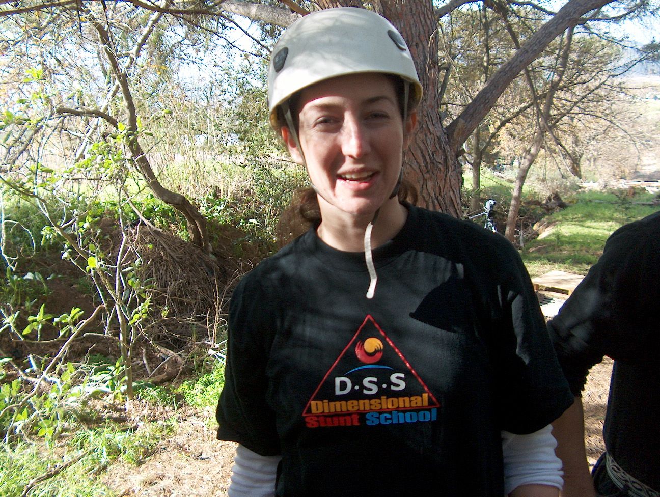 A trainee in a climbing helmet and DSS T-shirt on an outdoor climb