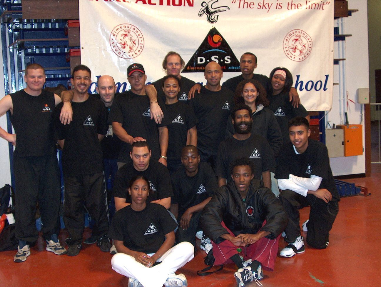 The first Dimensional Stunt School graduates in 2002, posed under a DSS banner reading The sky is the limit