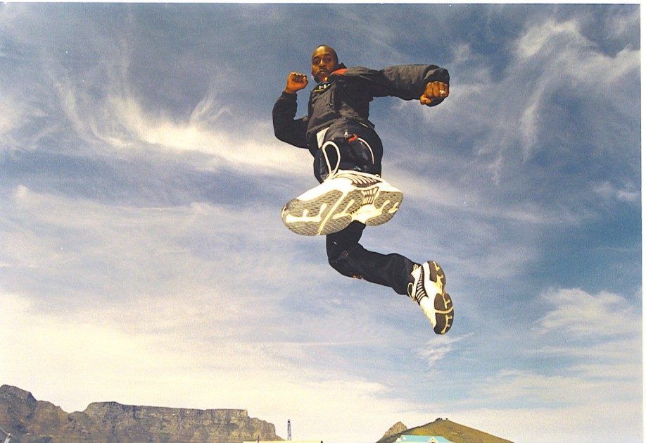Sensei San Ndlovu in a flying kick against the sky
