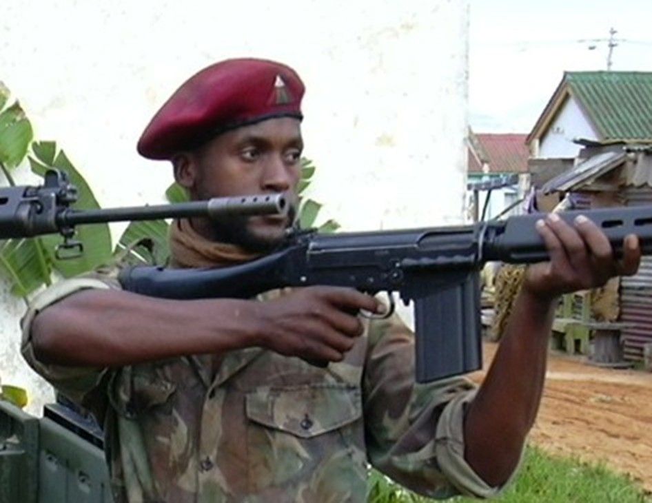 Sensei San Ndlovu in a red beret aiming a rifle on set