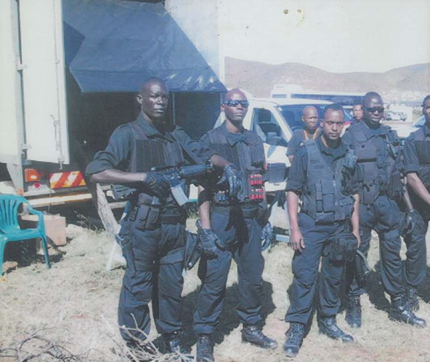 Performers in black tactical gear with rifles, on the Lord of War location